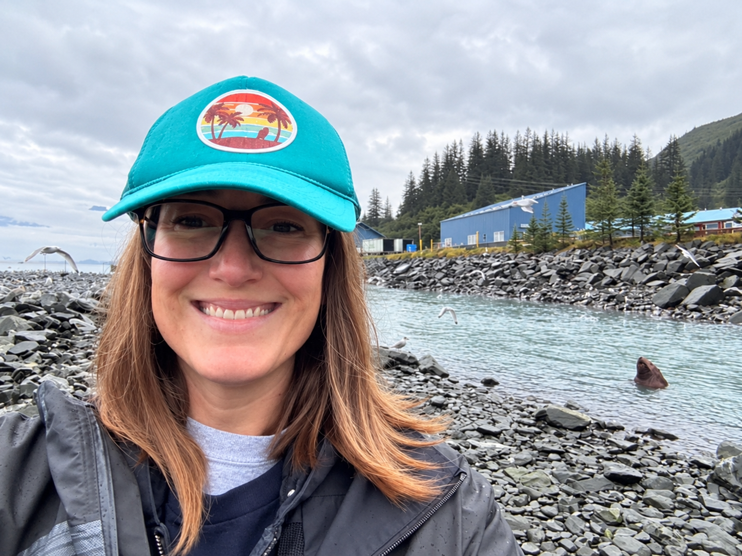 Jennifer smiling by the water with a sea lion in the background
